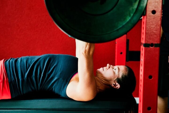 Woman performs bench press using a barbell