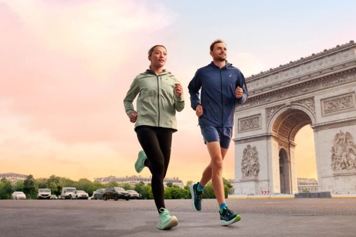 Male and female runners wearing Asics Gel-Nimbus 26 run past Arc de Triomphe